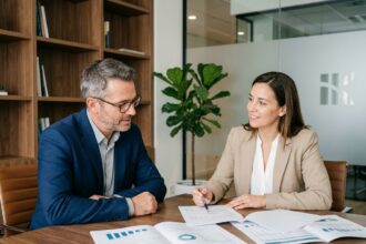 Conseiller en gestion de patrimoine expliquant une stratégie d'assurance décès à un client lors d'un rendez-vous professionnel
