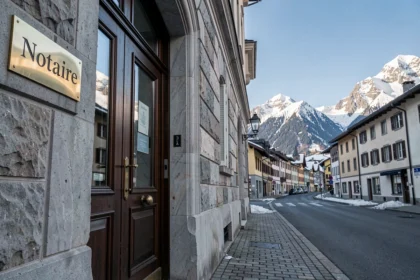 Entrée d'un office notarial en Haute-Savoie avec façade en pierre et plaque en laiton, montagnes enneigées en arrière-plan