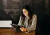 woman wearing white dress shirt using holding black leather case on brown wooden table