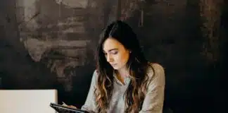 woman wearing white dress shirt using holding black leather case on brown wooden table