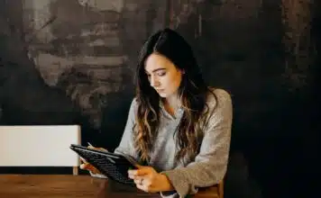 woman wearing white dress shirt using holding black leather case on brown wooden table